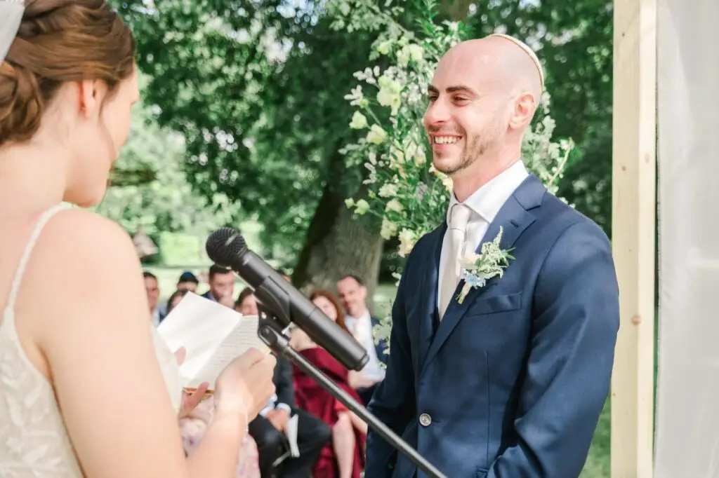 Marié souriant et ému écoutant les vœux de la mariée pendant la cérémonie au Château Gassies à Bordeaux.