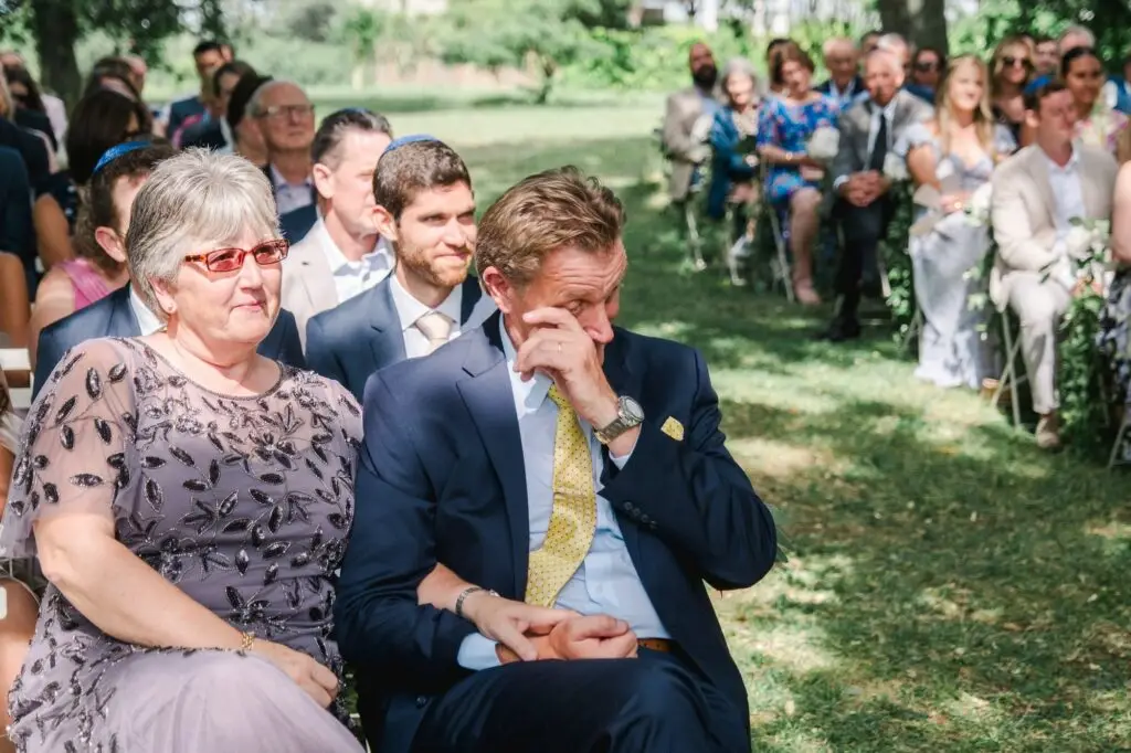 Père du marié ému essuyant une larme pendant la cérémonie de mariage au Château Gassies à Bordeaux.