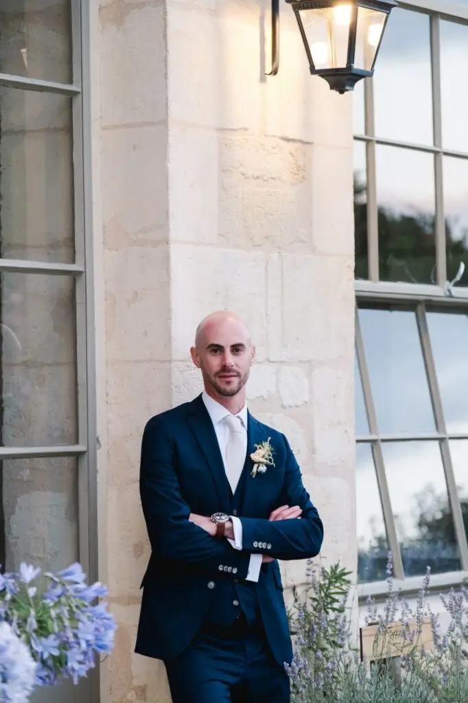 Portrait du marié en costume devant la façade du Château Gassies à Bordeaux lors du reportage de mariage