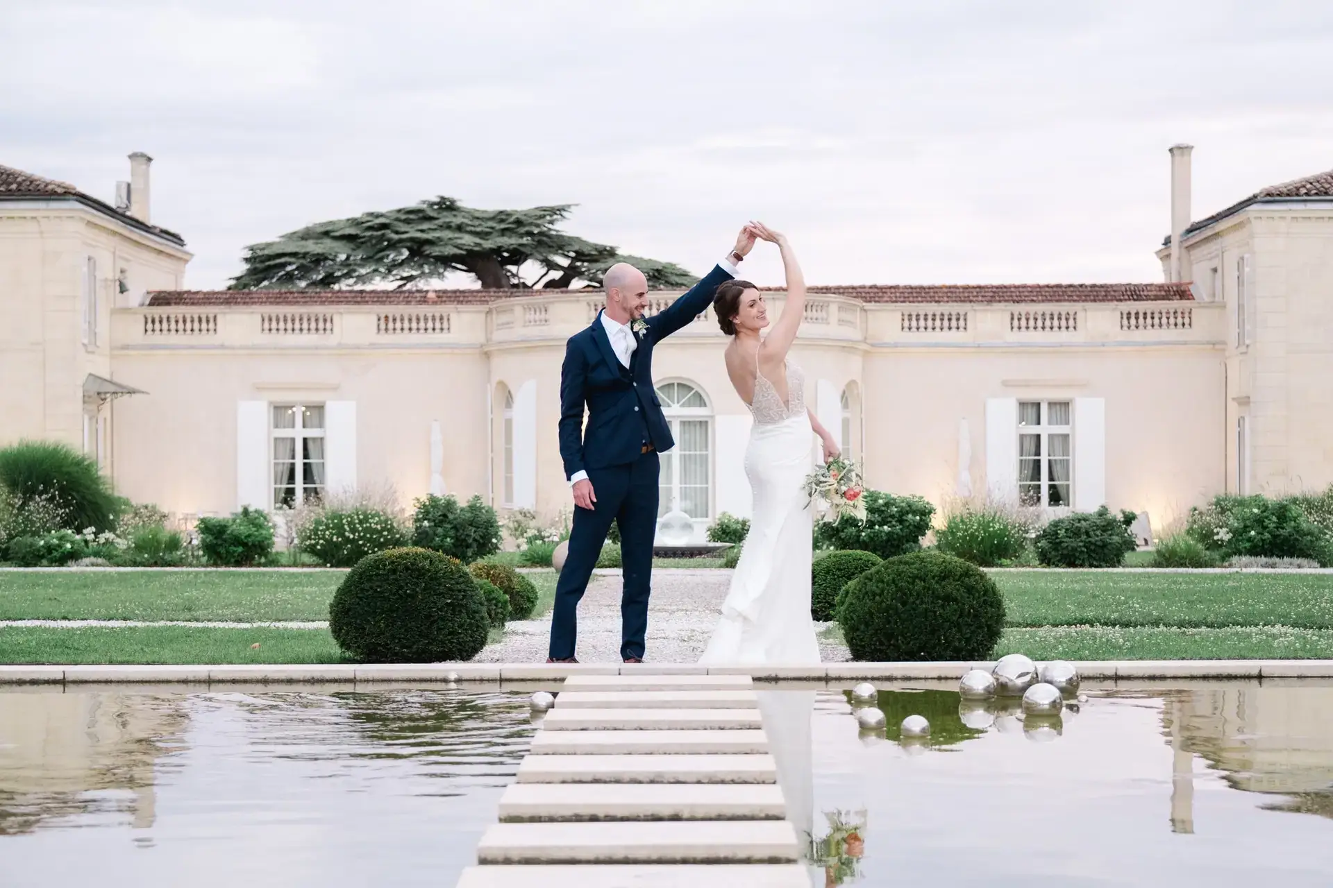 Les mariés dansent devant la façade du Château Gassies à Bordeaux pendant leur séance photo de mariage