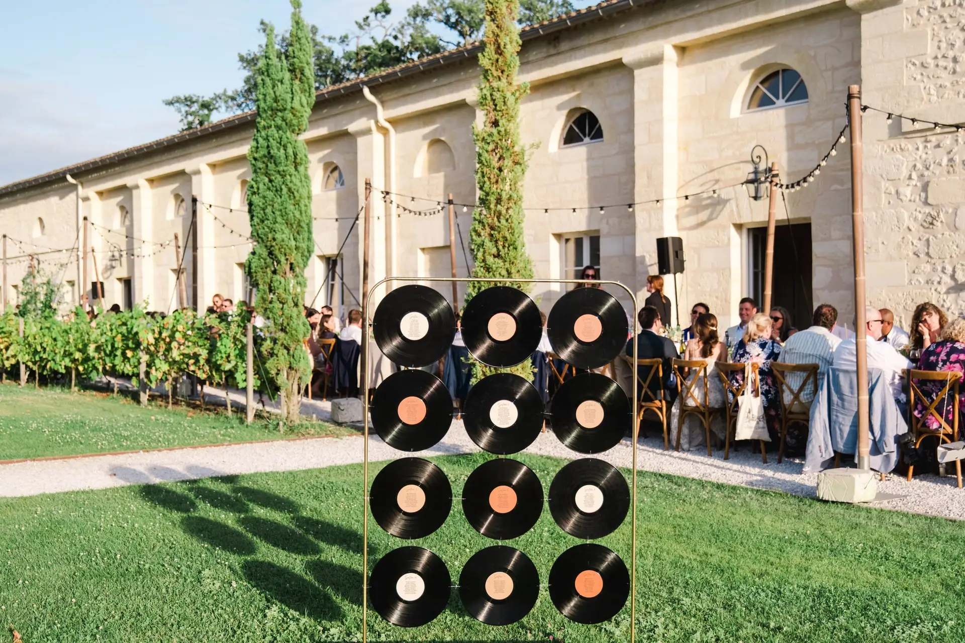 Installation décorative avec disques vinyles lors de la réception de mariage au Château Gassies à Bordeaux, avec les invités attablés en extérieur