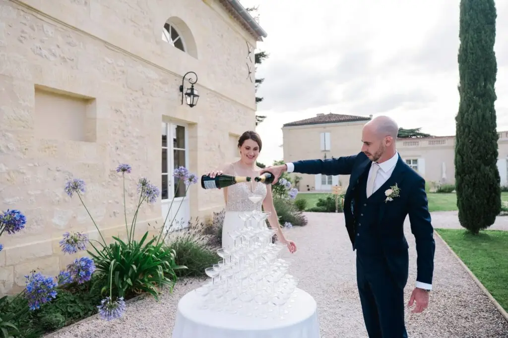 Les mariés versent le champagne dans une pyramide de coupes lors de leur réception au Château Gassies