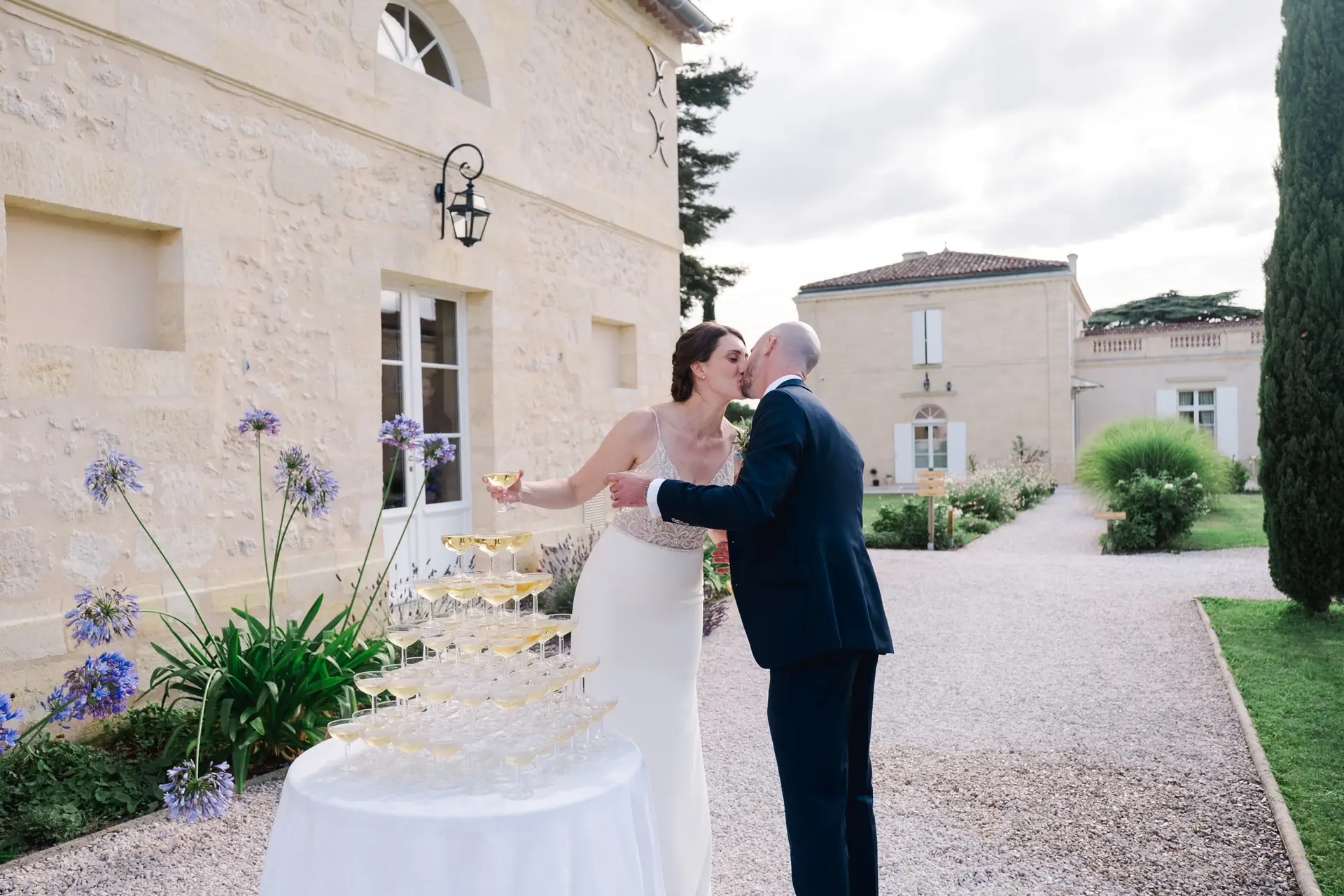 Les mariés s’embrassent après avoir servi le champagne pendant leur mariage au Château Gassies