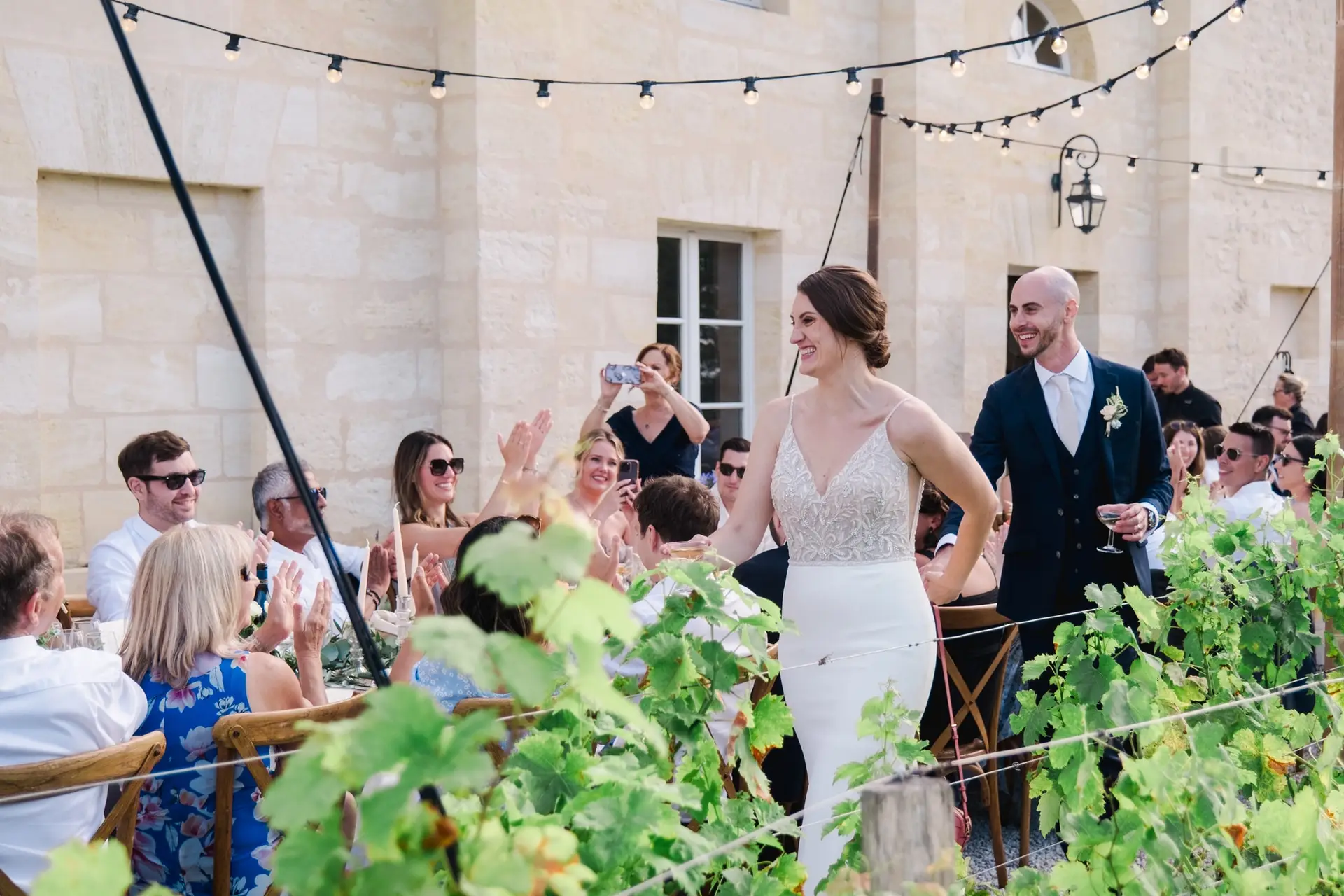 Les mariés marchent entre les tables sous les applaudissements des invités lors du dîner de mariage au château Gassies