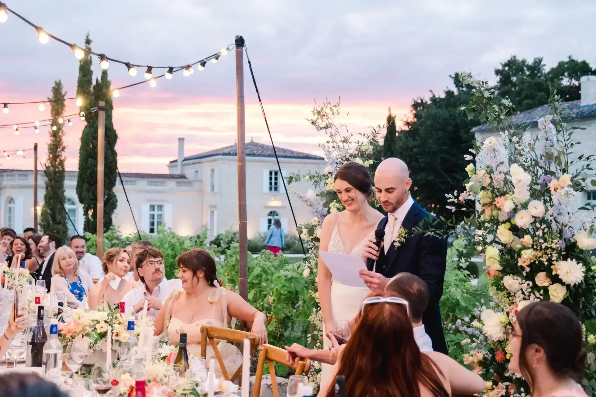 Les mariés lisent un discours devant leurs invités lors du dîner de mariage au château Gassies au coucher du soleil