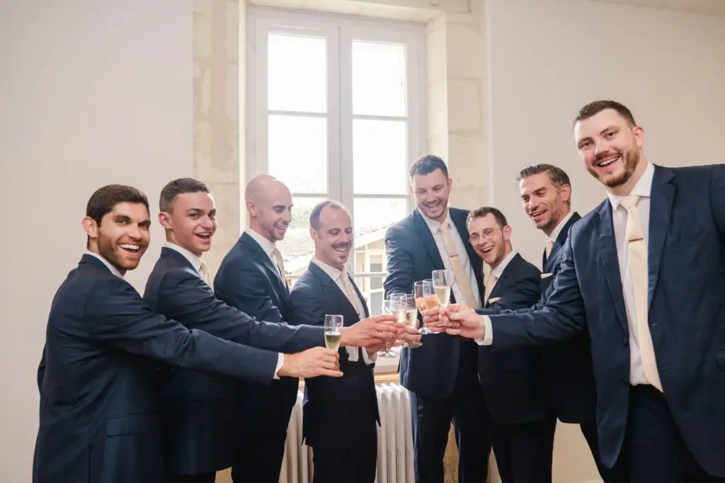 Garçons d’honneur trinquant au champagne pendant les préparatifs de mariage au Château Gassies à Bordeaux.