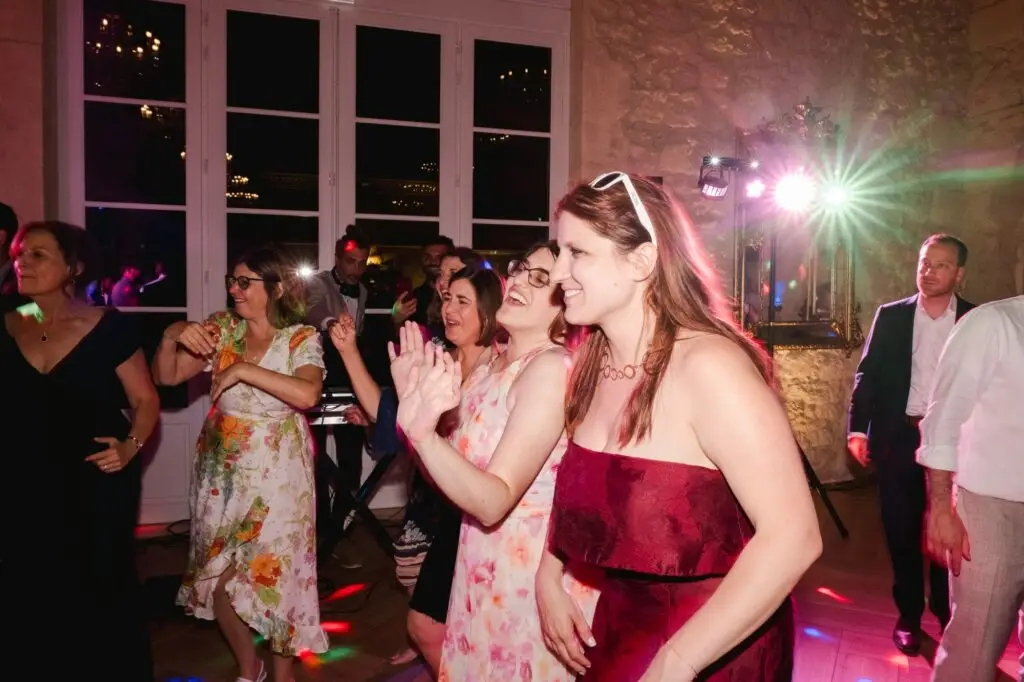 Plusieurs invitées dansent et rient ensemble sur la piste de danse lors de la soirée de mariage.