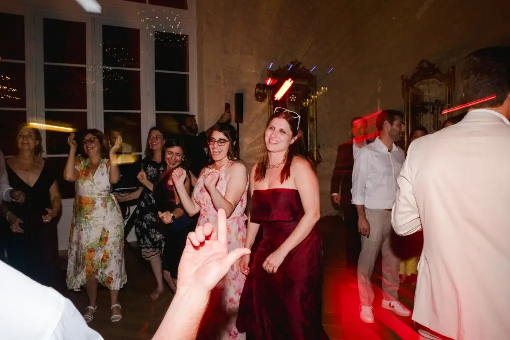 Les invités dansent sur la piste de danse sous des lumières colorées dans une salle de réception en pierre.