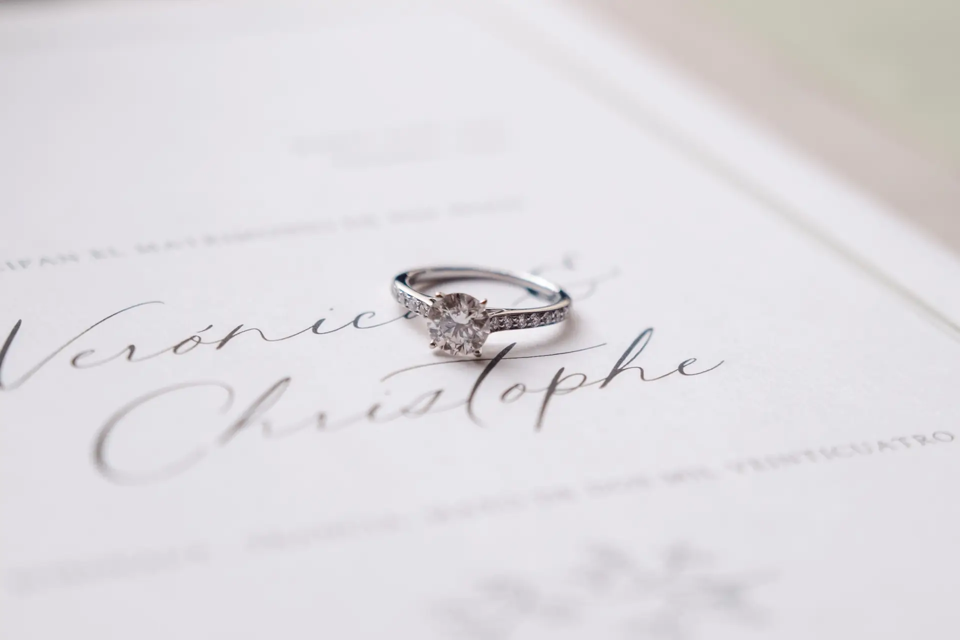 Gros plan sur une alliance de mariage posée sur un faire-part élégant au Château Pape Clément à Pessac, photo par Julien Boyer photographe de mariage