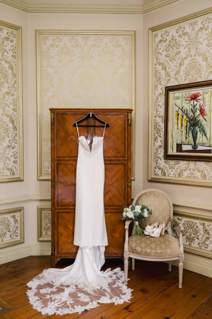 Robe de mariée suspendue dans une chambre élégante du Château Pape Clément à Pessac, préparatifs de mariage photographiés par Julien Boyer
