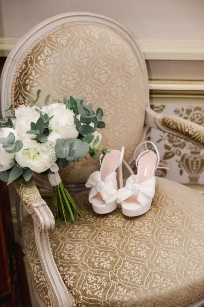 Bouquet de la mariée et chaussures de mariage posés sur un fauteuil lors des préparatifs au Château Pape Clément, photo par Julien Boyer photographe de mariage