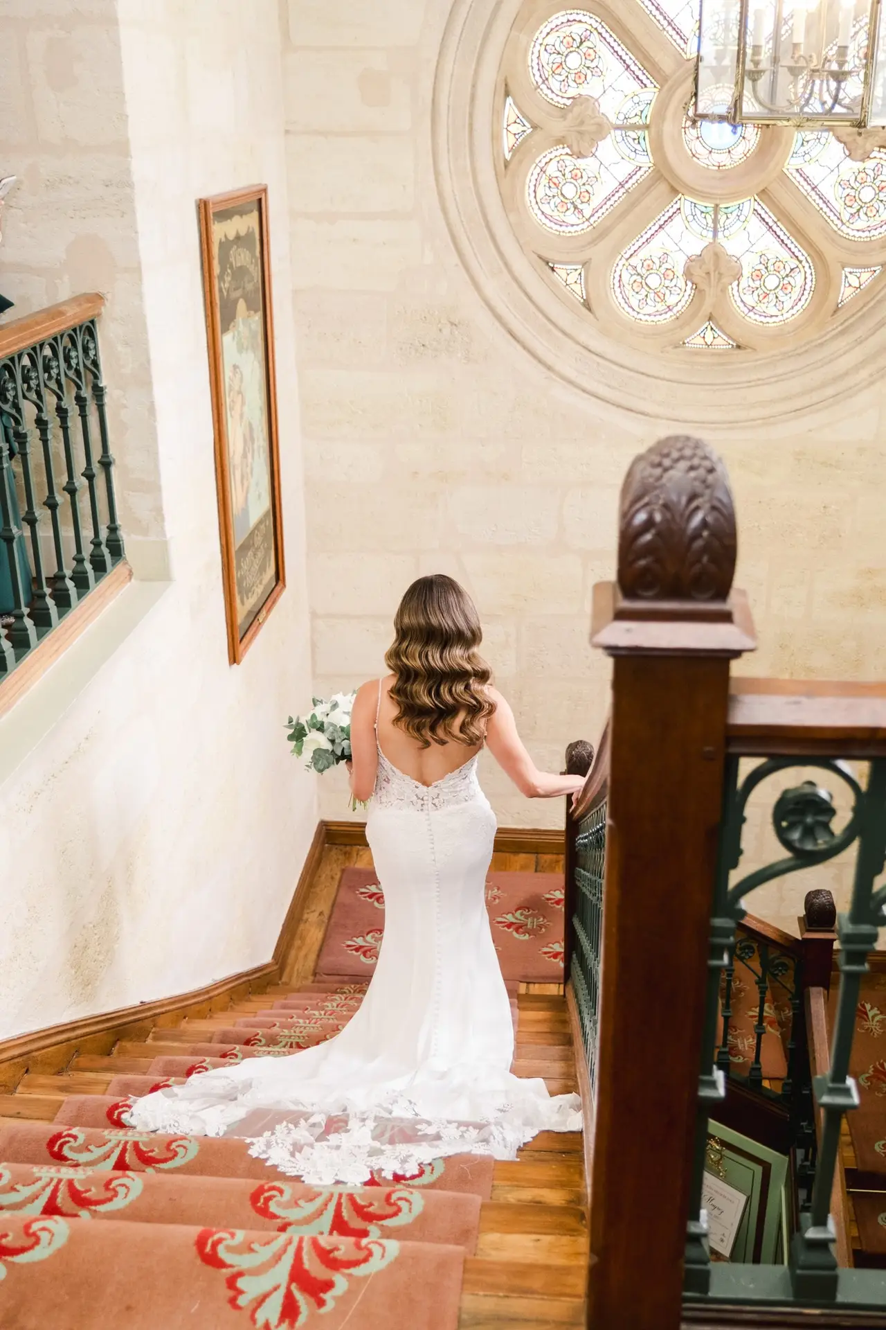 La mariée descend l’escalier du Château Pape Clément à Pessac, robe de mariage avec traîne photographiée par Julien Boyer