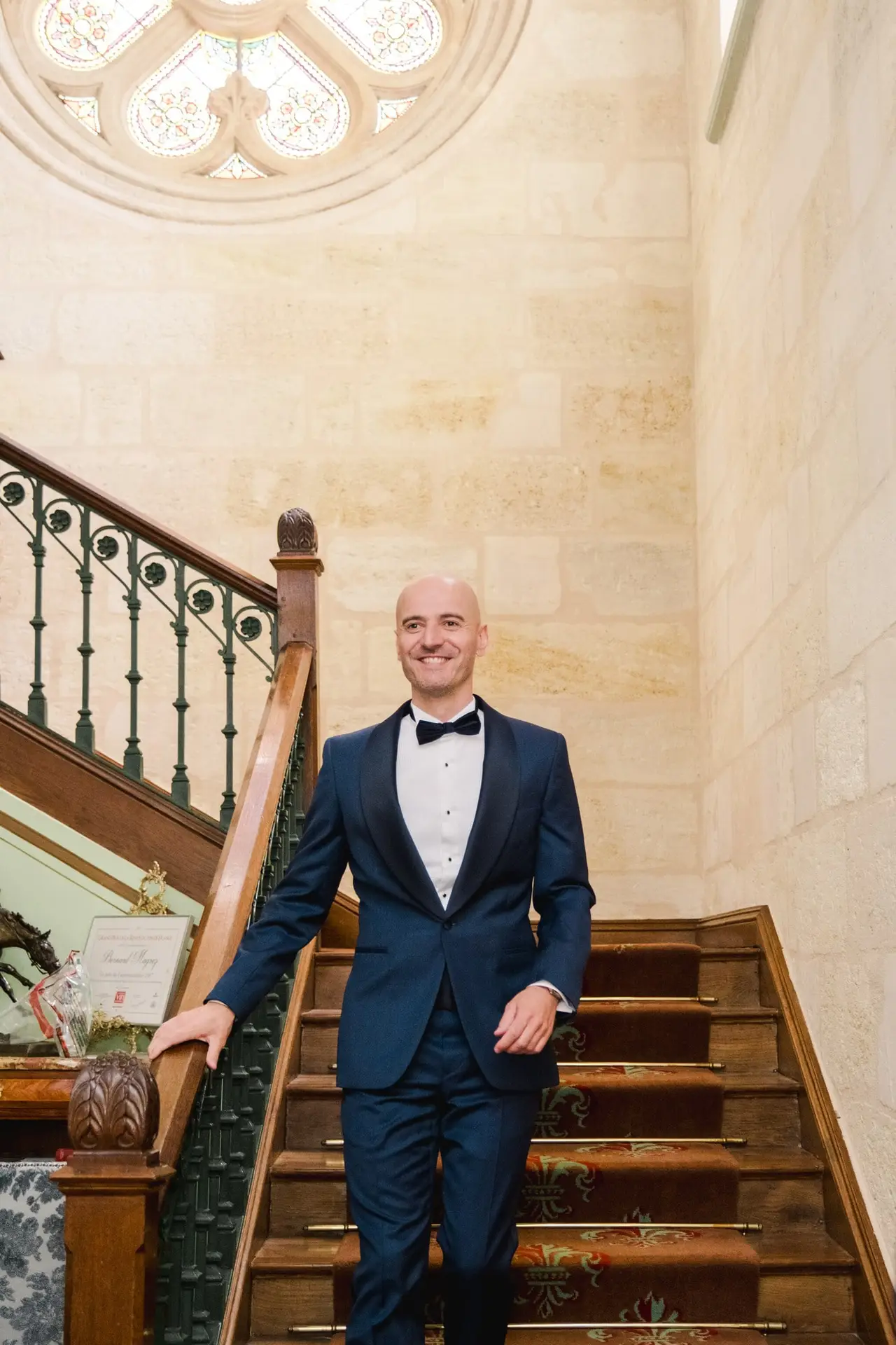 Portrait du marié en costume descendant l’escalier du Château Pape Clément à Pessac avant la cérémonie de mariage, photo par Julien Boyer