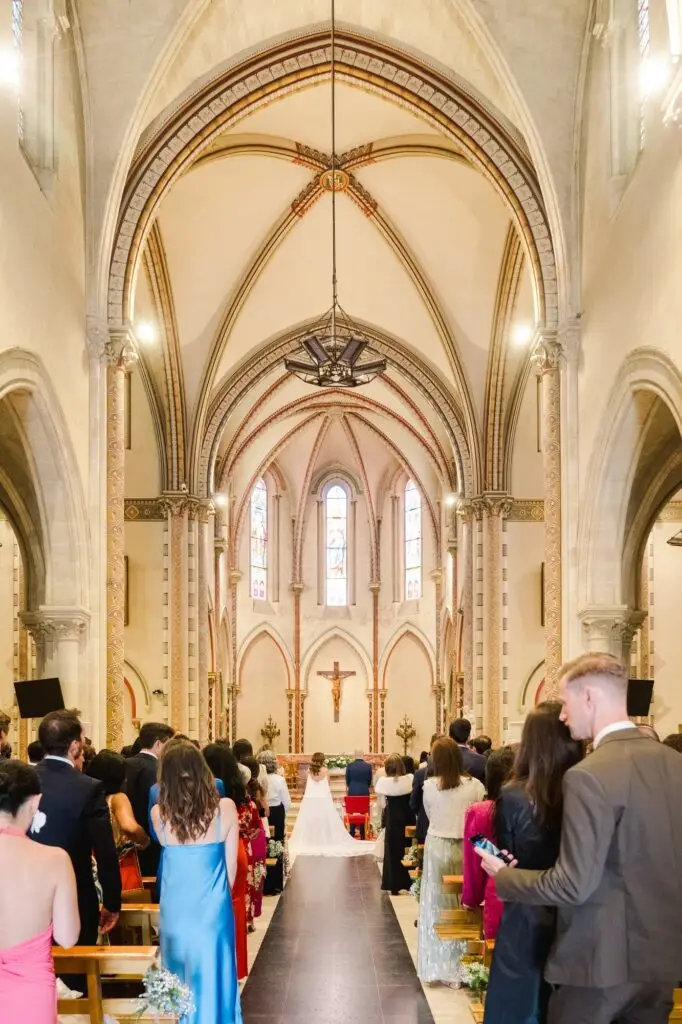 Vue d’ensemble de la cérémonie de mariage à l’église de Caudéran à Bordeaux avec les invités debout dans la nef, photo par Julien Boyer
