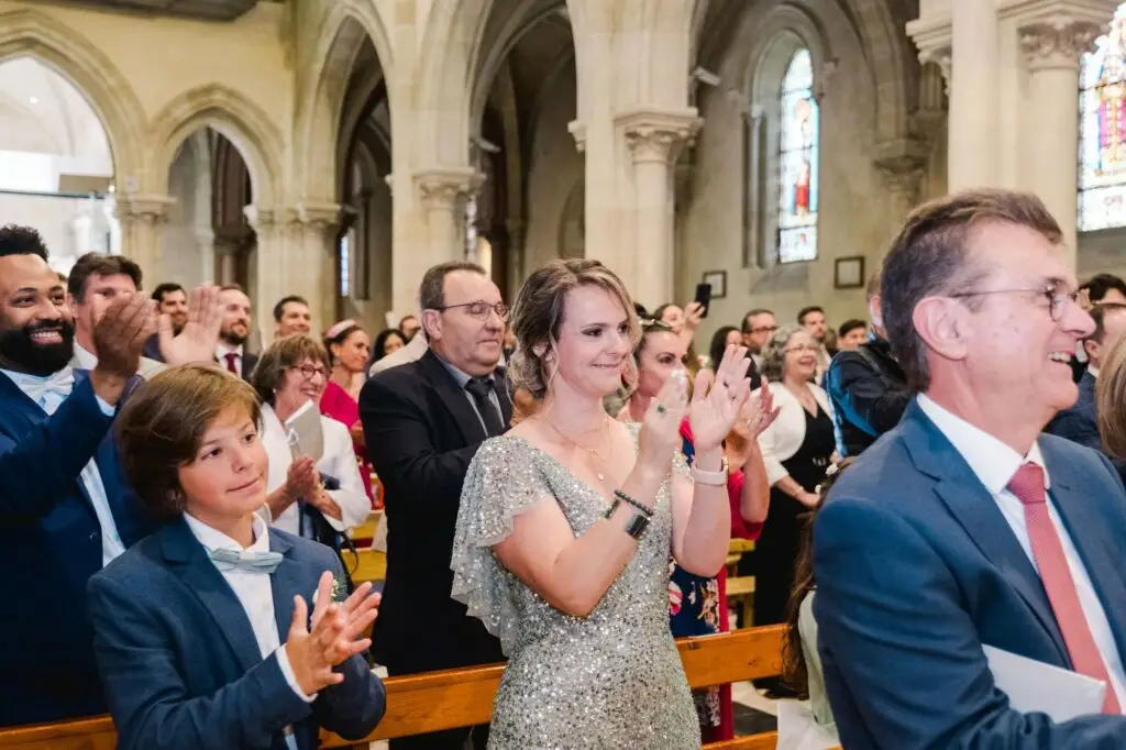 Proches et invités applaudissent et sourient pendant la cérémonie de mariage à l’église de Caudéran à Bordeaux, reportage photo par Julien Boyer
