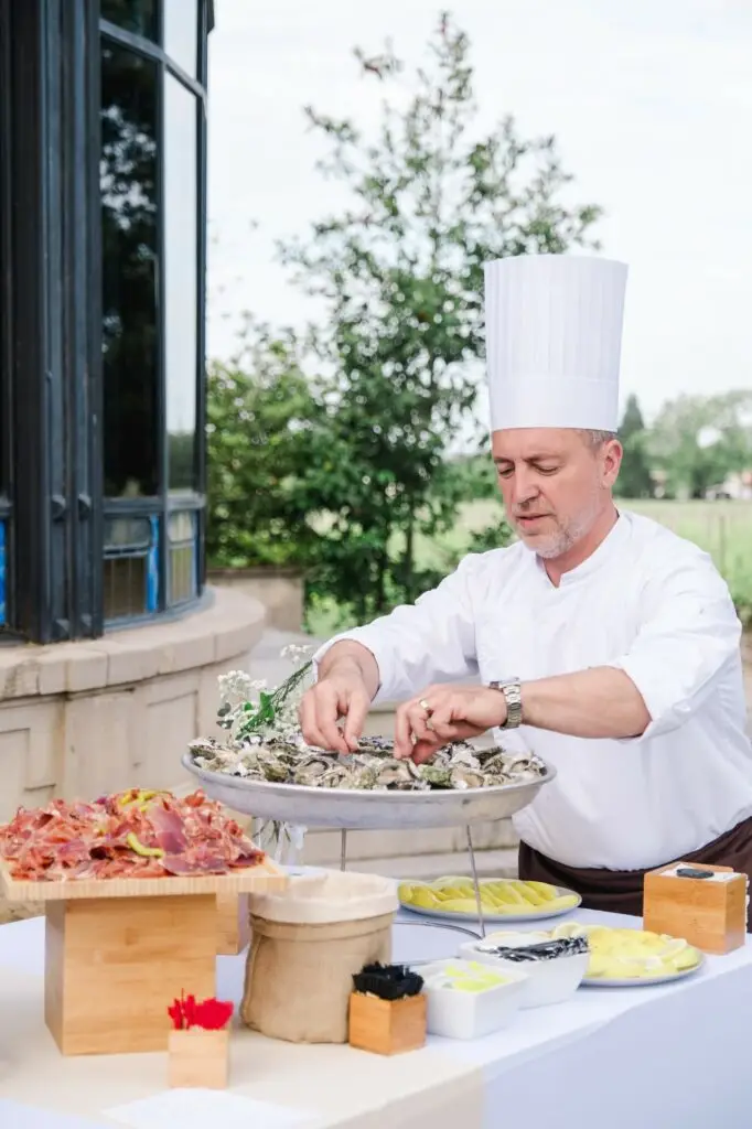 Chef préparant des huîtres lors du cocktail de mariage au Château Pape Clément à Pessac, animation culinaire photographiée par Julien Boyer