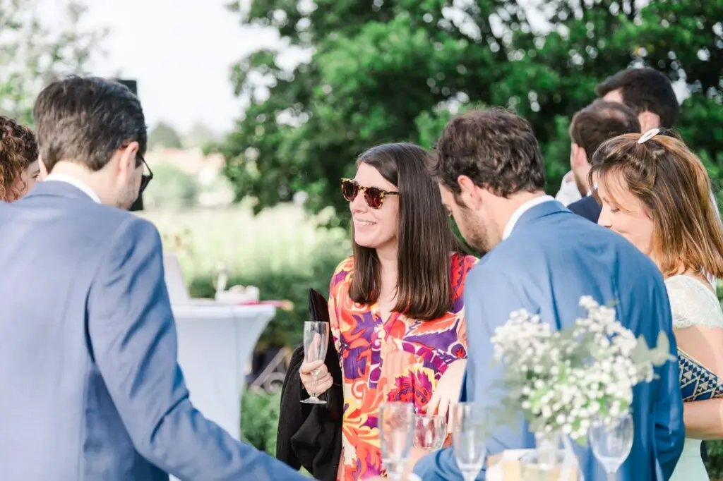 Invités discutant autour de tables hautes pendant le cocktail de mariage au Château Pape Clément à Pessac, photo de mariage par Julien Boyer