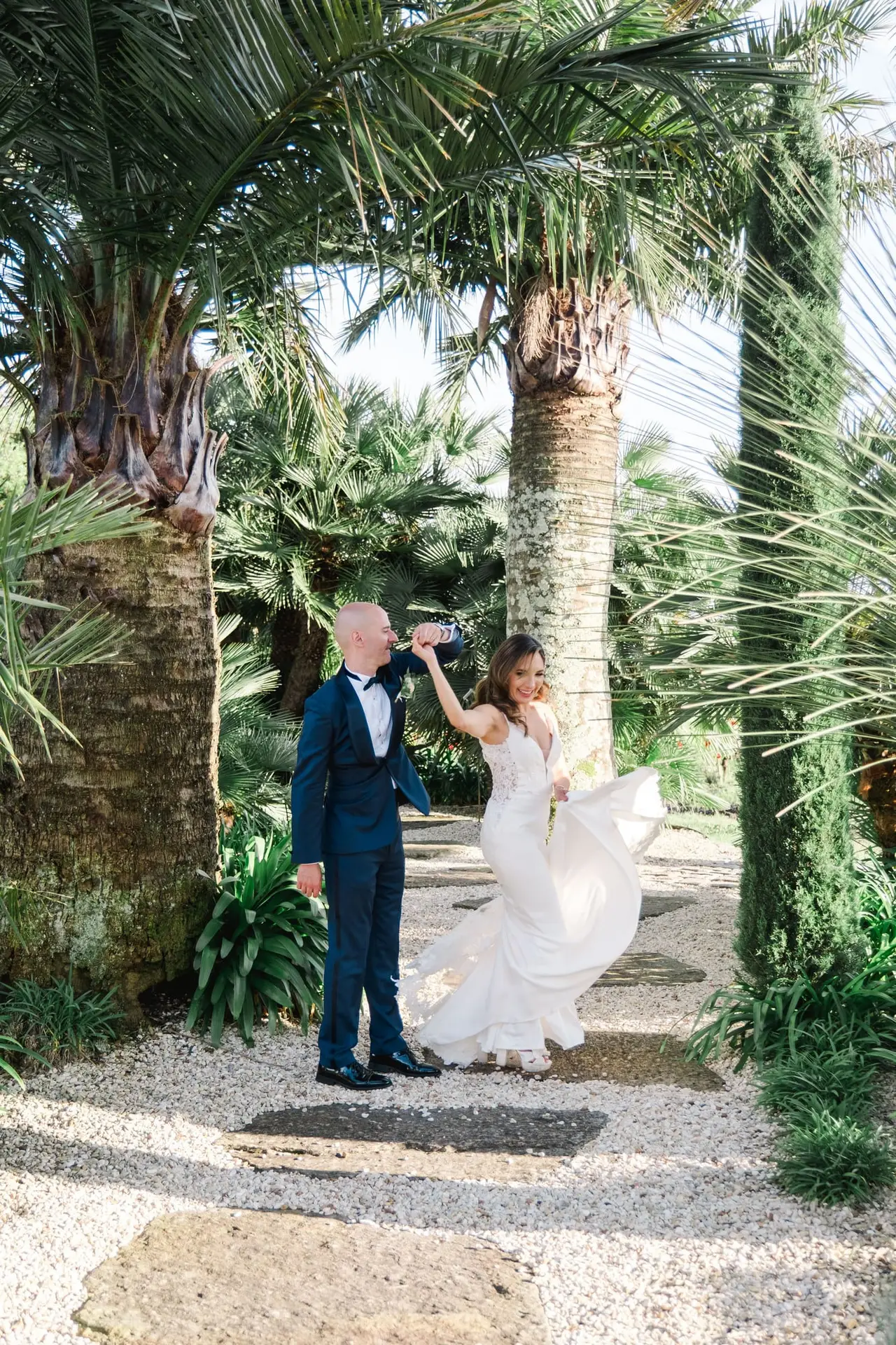 Les mariés se tiennent par la main sous les palmiers lors de leur séance photo de couple au Château Pape Clément à Pessac, photo Julien Boyer
