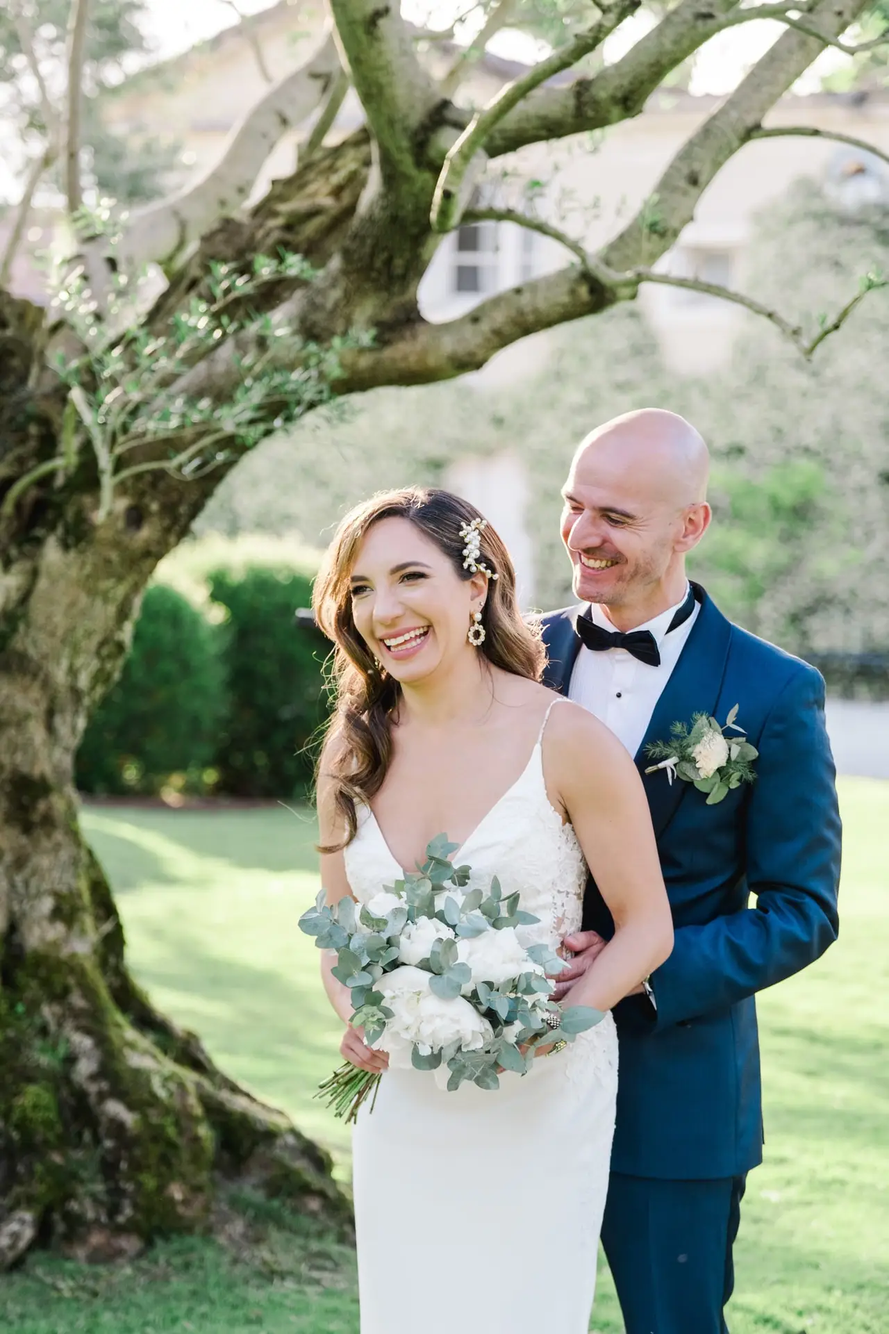 Moment complice et spontané des mariés enlacés sous un arbre dans les jardins du Château Pape Clément à Pessac, photo de mariage par Julien Boyer