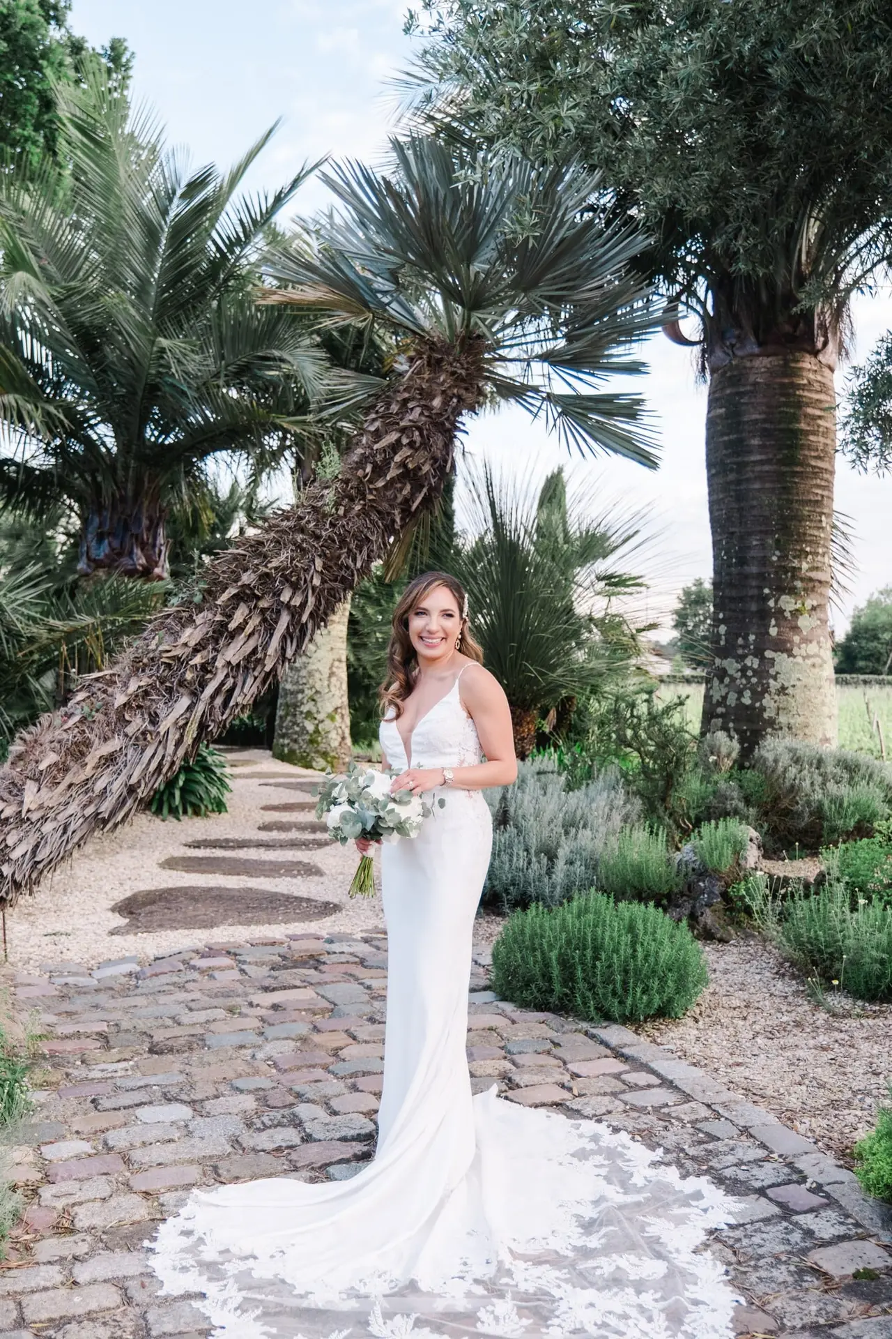 Portrait de la mariée en robe de mariage sous les palmiers dans les jardins du Château Pape Clément à Pessac, photo par Julien Boyer photographe de mariage