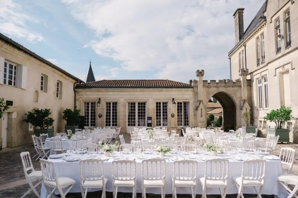 Tables dressées pour le dîner de mariage en extérieur dans la cour du Château Pape Clément à Pessac, décoration élégante photographiée par Julien Boyer
