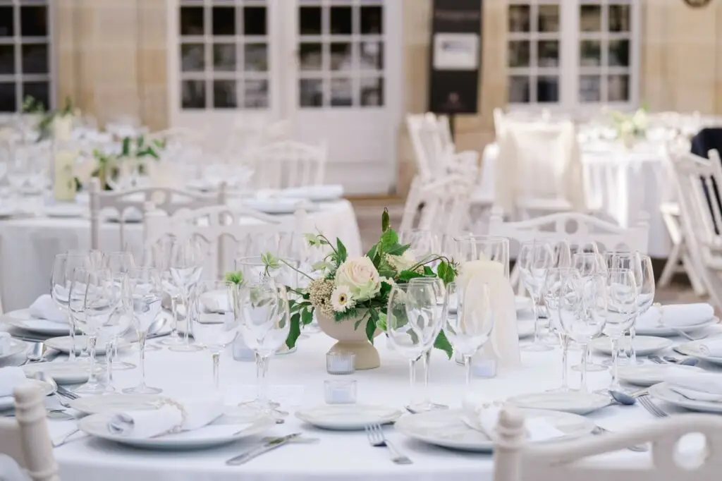 Décoration de table de mariage avec vaisselle blanche et centre de table fleuri lors du dîner au Château Pape Clément à Pessac, photo par Julien Boyer