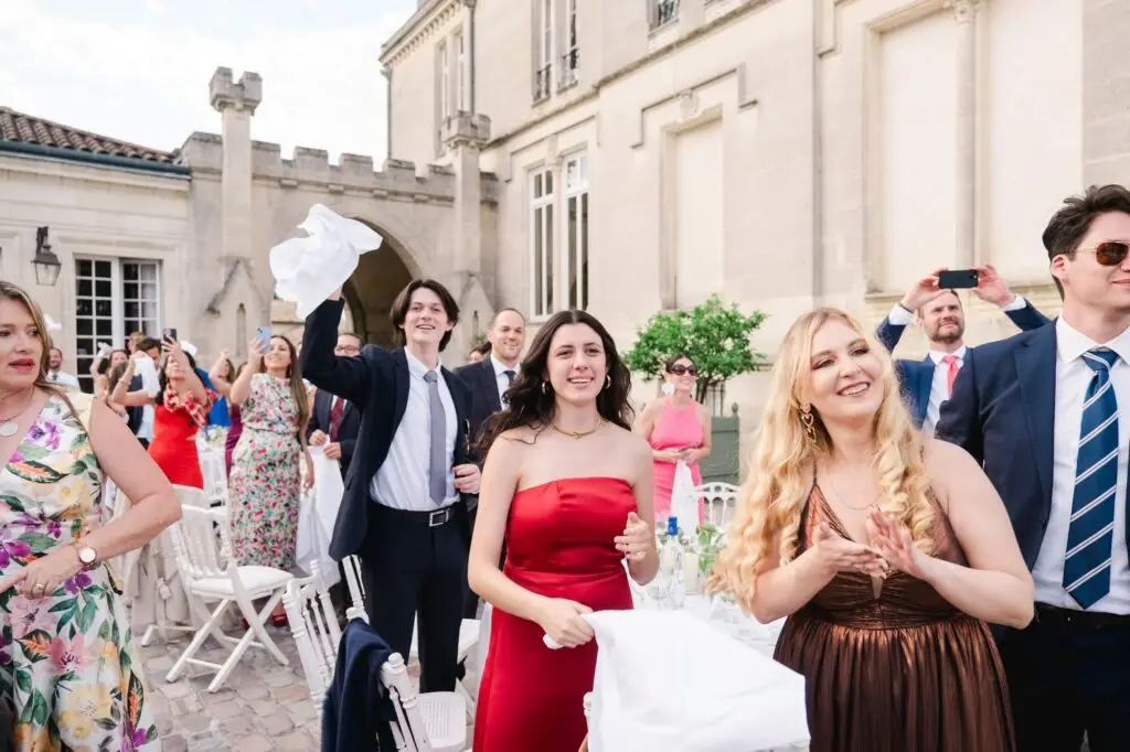 Invités applaudissant et célébrant les mariés pendant la réception de mariage au Château Pape Clément à Pessac, reportage photo par Julien Boyer