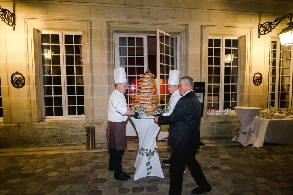 Arrivée du gâteau de mariage en soirée dans la cour du Château Pape Clément à Pessac, mise en scène élégante photographiée par Julien Boyer