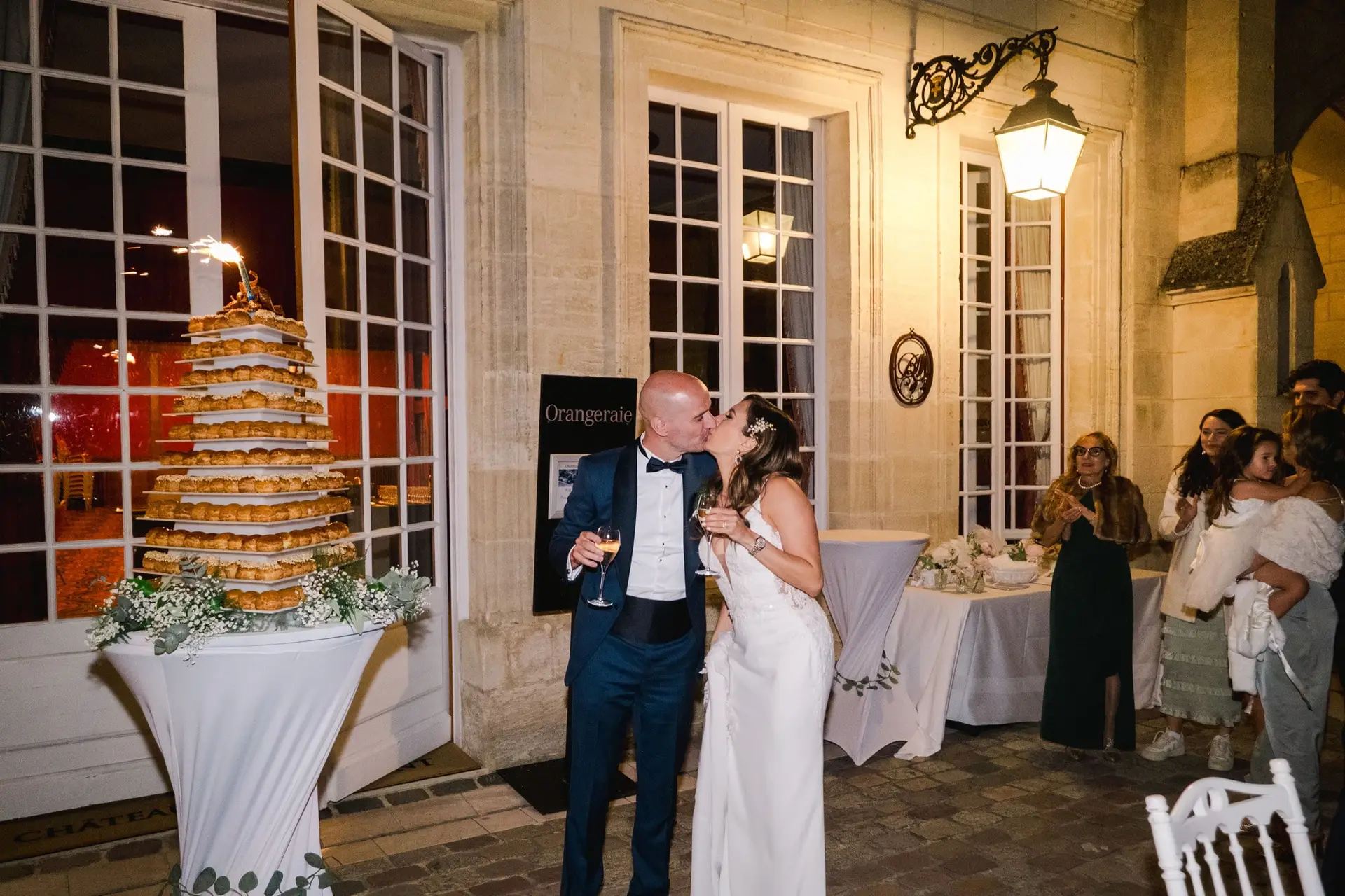 Les mariés s’embrassent devant le gâteau de mariage au Château Pape Clément à Pessac lors de la soirée, photo de mariage par Julien Boyer