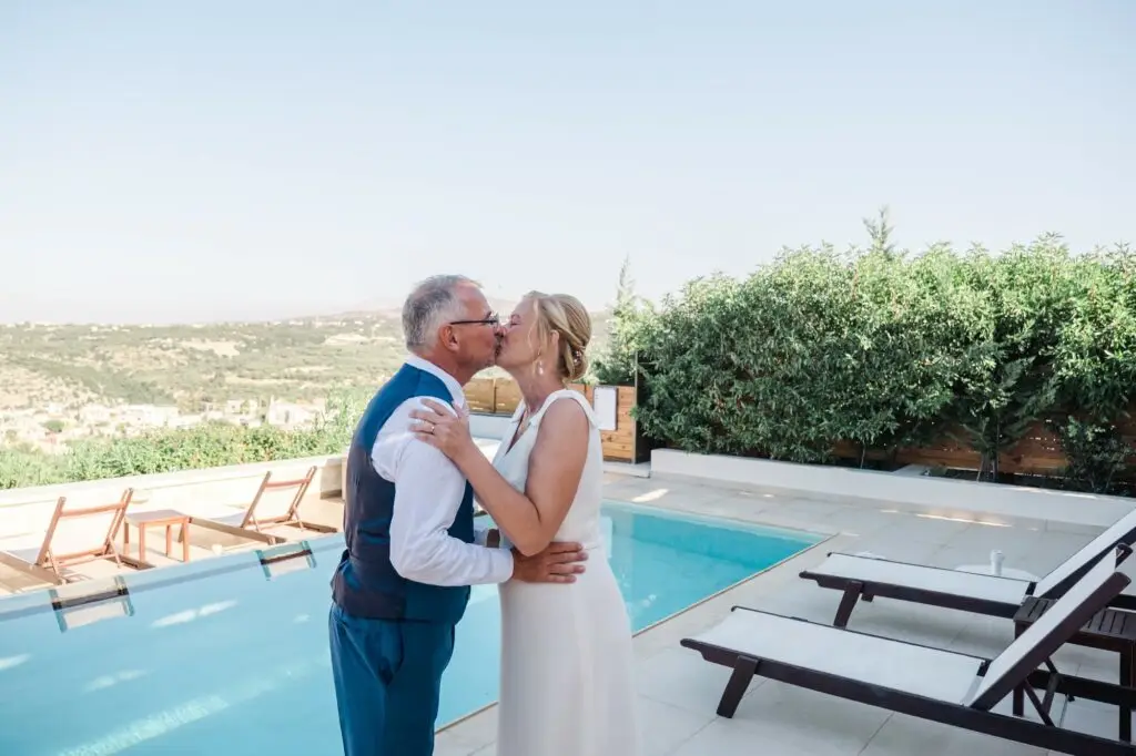 Baiser des mariés au bord de la piscine lors de leur mariage à Rethymnon en Crète, moment intime et naturel photographié par Julien Boyer photographe de mariage