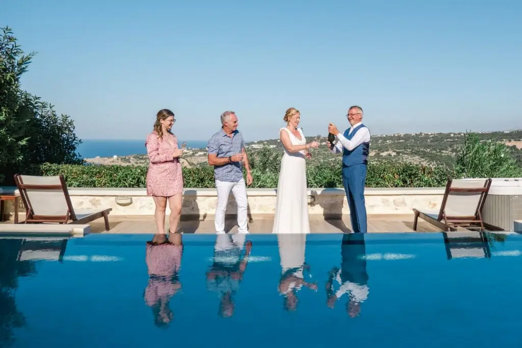 Toast de mariage avec les proches au bord de la piscine à Rethymnon en Crète, ambiance conviviale et joyeuse photographiée par Julien Boyer photographe de mariage