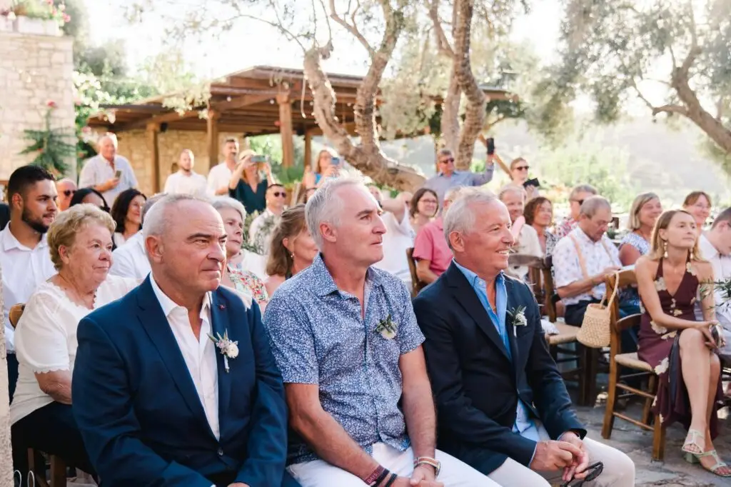 Invités assis pendant la cérémonie de mariage à Agreco Farm près de Rethymnon en Crète, attentifs et émus photographiés par Julien Boyer