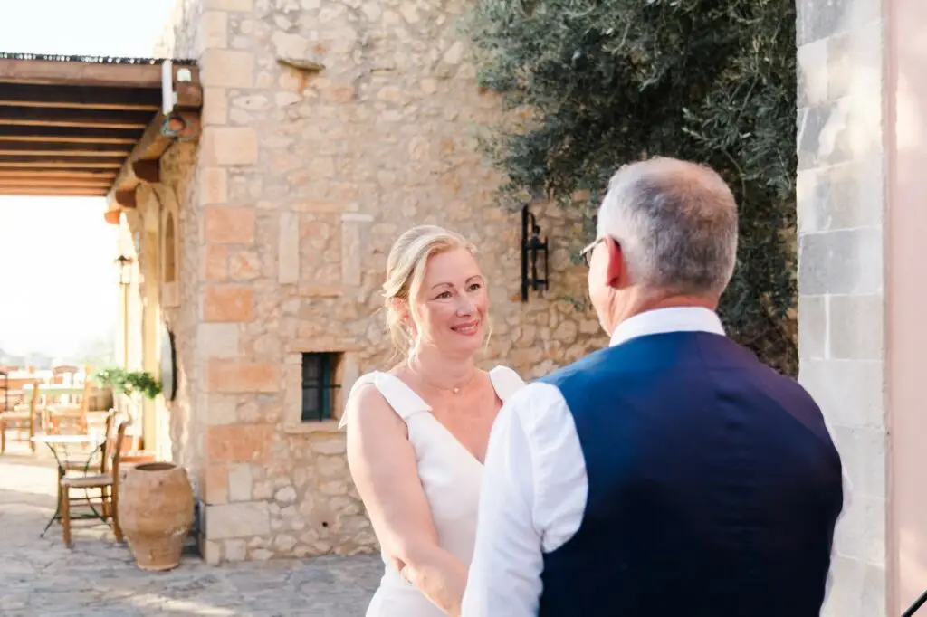 Portrait de la mariée souriante pendant la cérémonie de mariage à Agreco Farm en Crète, moment d’émotion capturé par Julien Boyer photographe de mariage