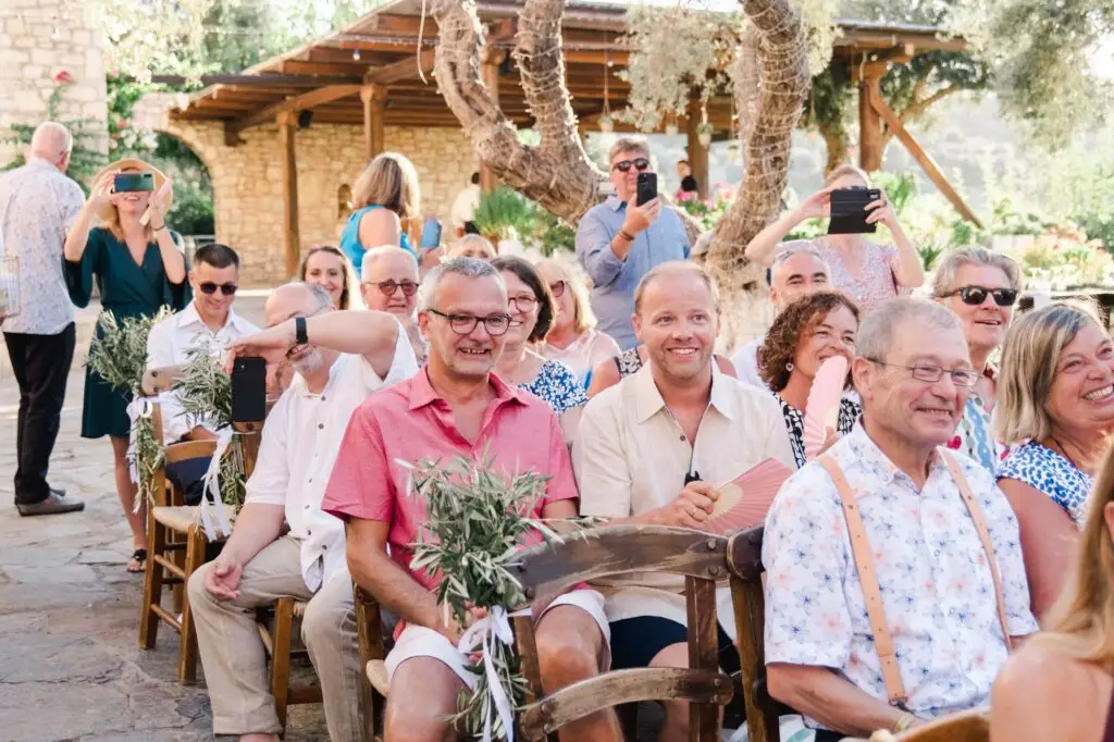 Invités souriants et émus pendant la cérémonie de mariage à Agreco Farm près de Rethymnon en Crète, reportage photo naturel par Julien Boyer