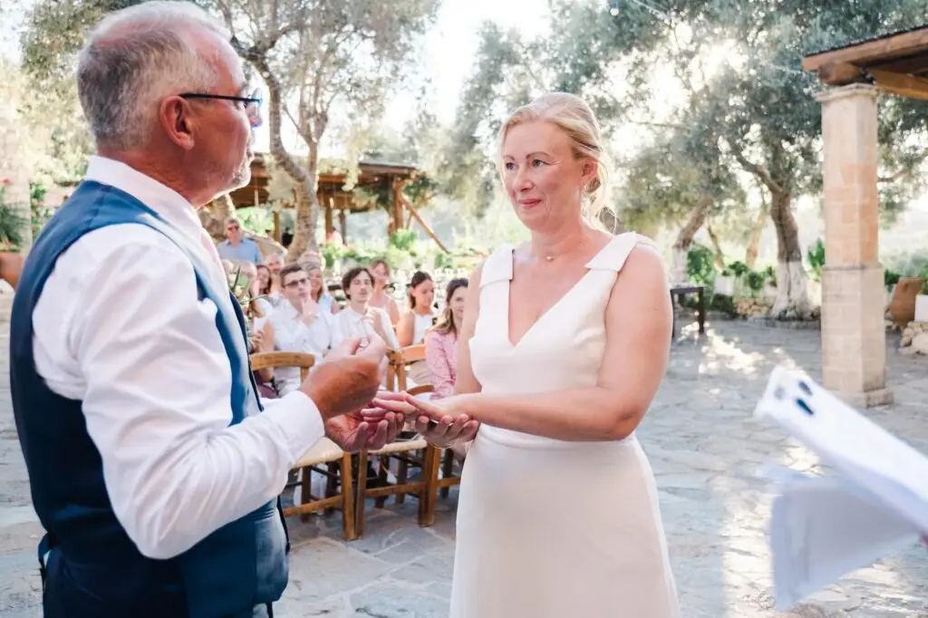 Moment d’émotion lors de l’échange des vœux à Agreco Farm en Crète, mariés se regardant pendant la cérémonie, reportage signé Julien Boyer photographe de mariage