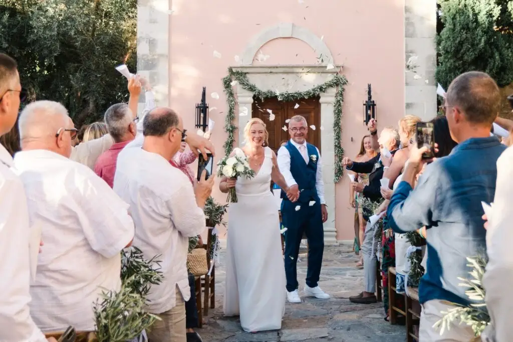 Sortie de cérémonie des mariés à Agreco Farm près de Rethymnon en Crète, invités lançant des pétales, reportage photo par Julien Boyer photographe de mariage