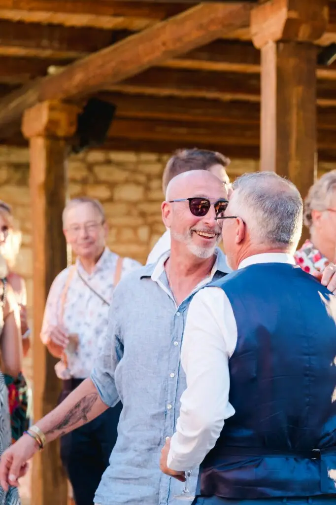 Invités échangeant et félicitant les mariés lors du cocktail de mariage à Agreco Farm en Crète, ambiance conviviale capturée par Julien Boyer