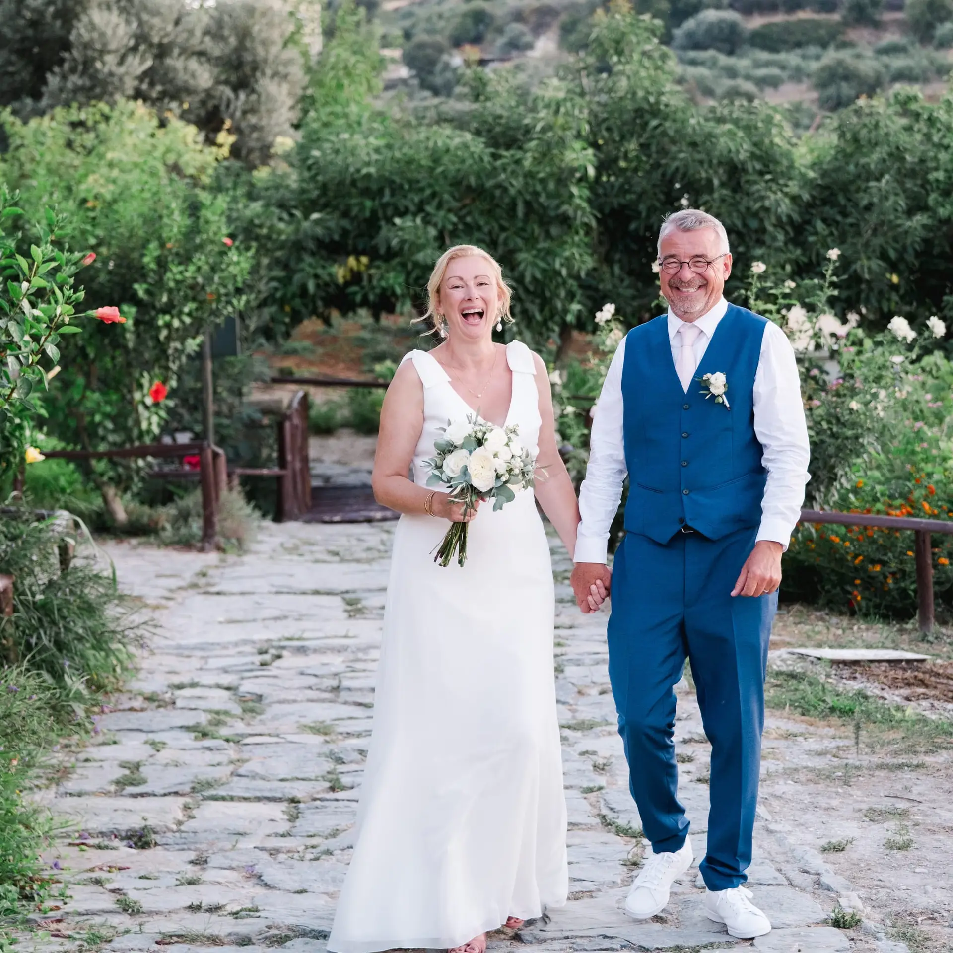 Portrait des mariés marchant main dans la main après leur cérémonie de mariage à Agreco Farm en Crète, photo naturelle par Julien Boyer photographe de mariage