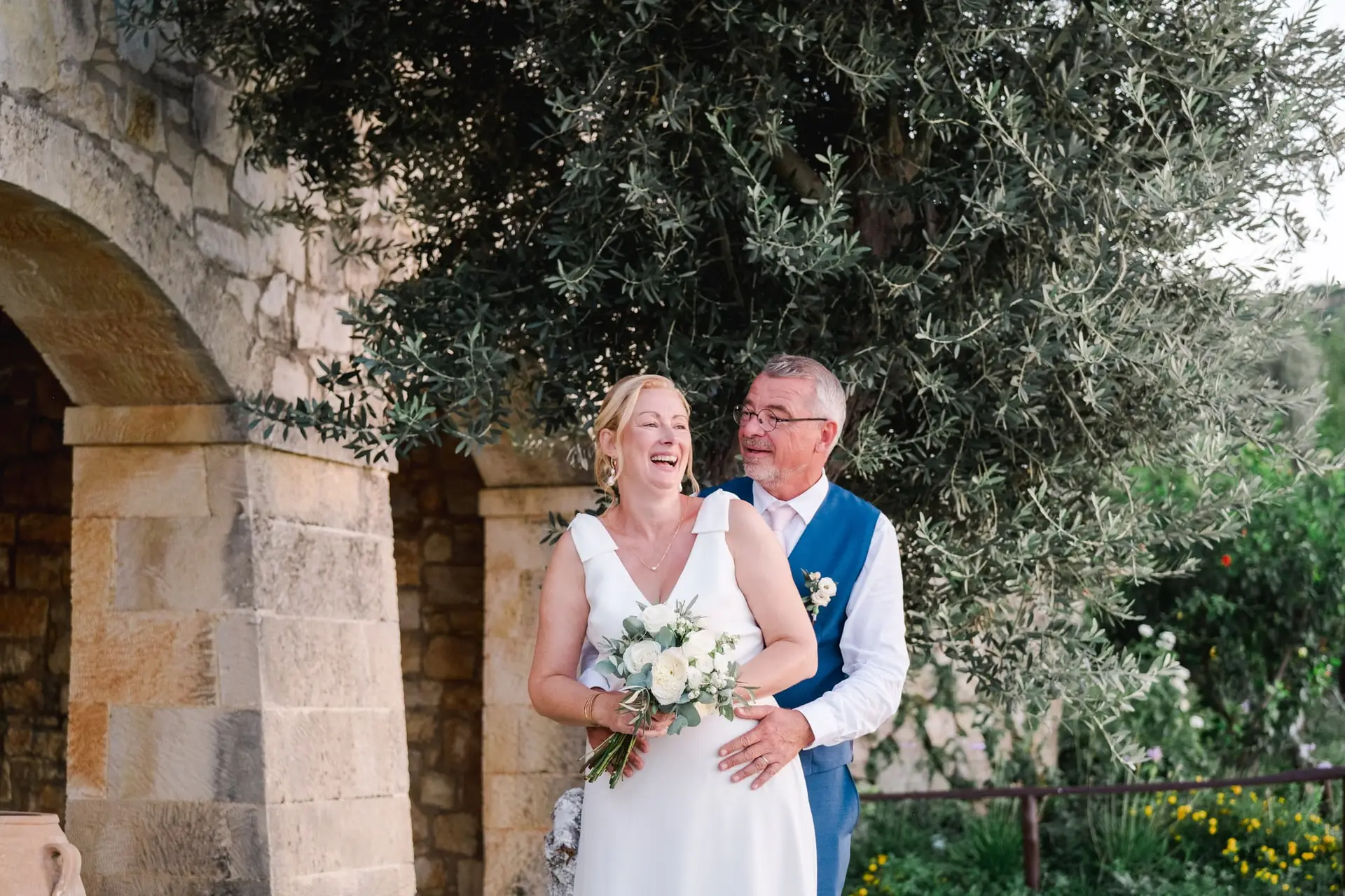 Portrait des mariés sous un olivier à Agreco Farm en Crète, couple complice dans un décor méditerranéen photographié par Julien Boyer photographe de mariage