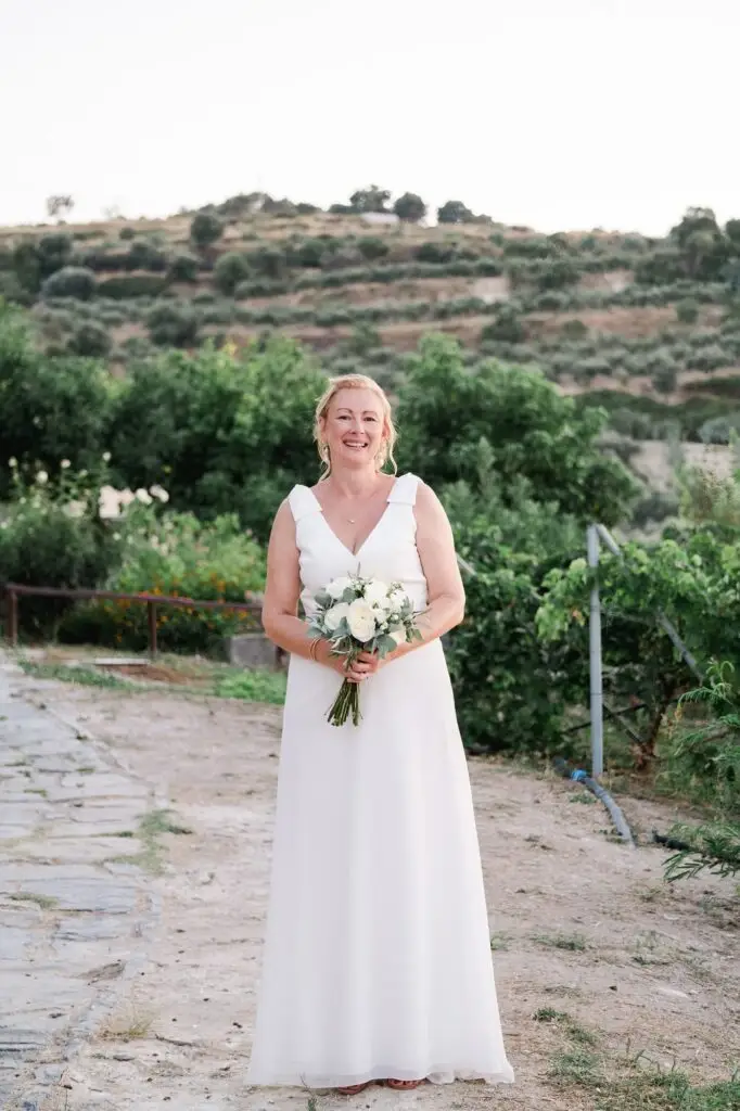 Portrait de la mariée tenant son bouquet lors de son mariage à Agreco Farm près de Rethymnon en Crète, photo naturelle par Julien Boyer photographe de mariage