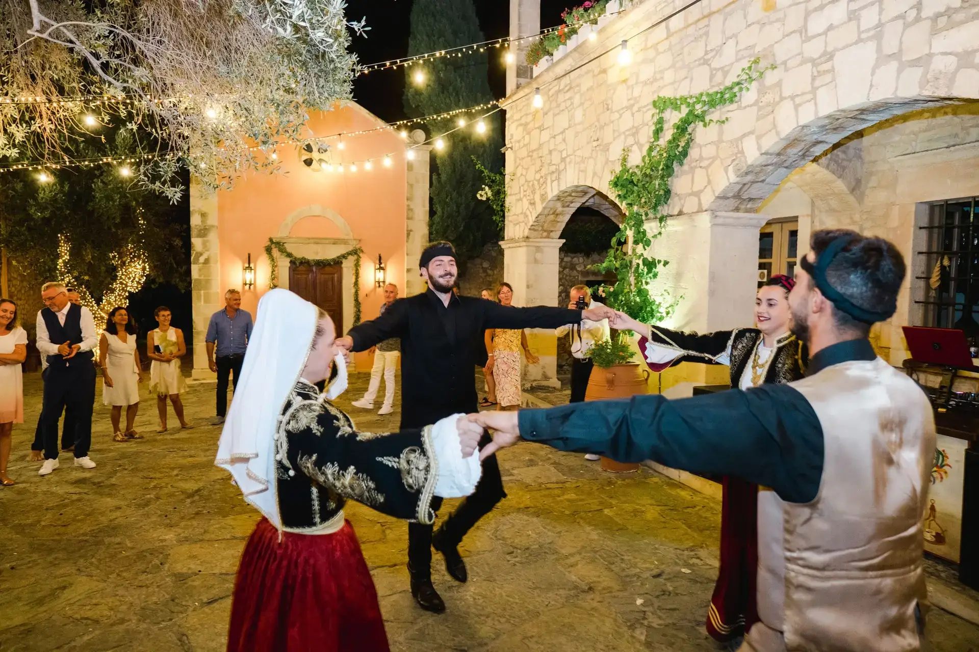 Danseurs en costumes traditionnels crétois se produisant lors d’un mariage à Rethymnon en Crète, ambiance festive en soirée photographiée par Julien Boyer photographe de mariage