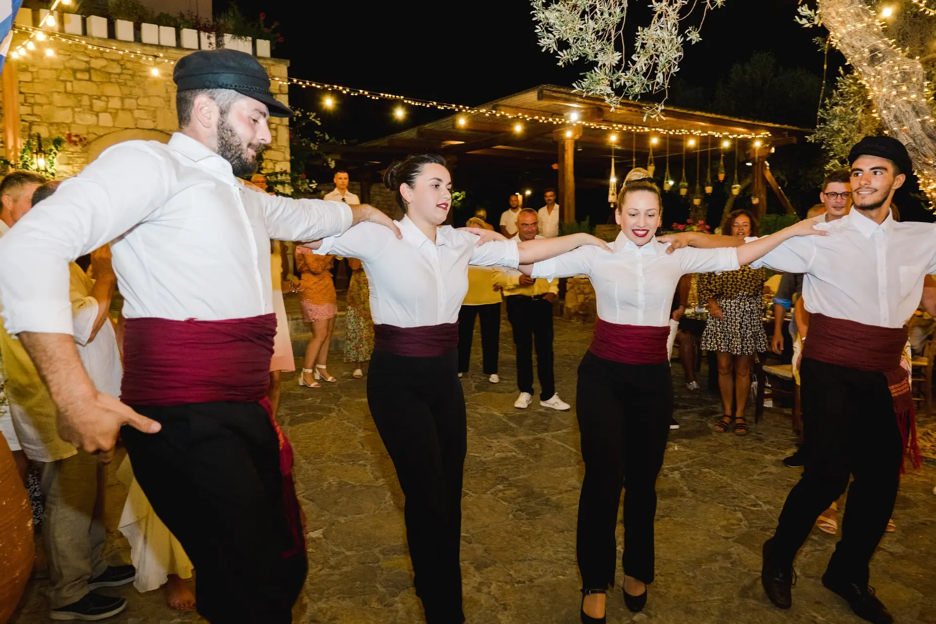 Invité dansant avec énergie sur la piste pendant la soirée de mariage en Crète, ambiance festive et lumières nocturnes
