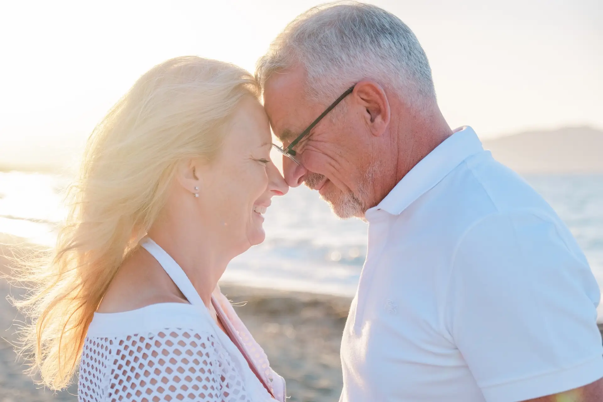 Portrait rapproché d’un couple se touchant le front sur une plage de Crète, lumière douce du soir et émotion naturelle