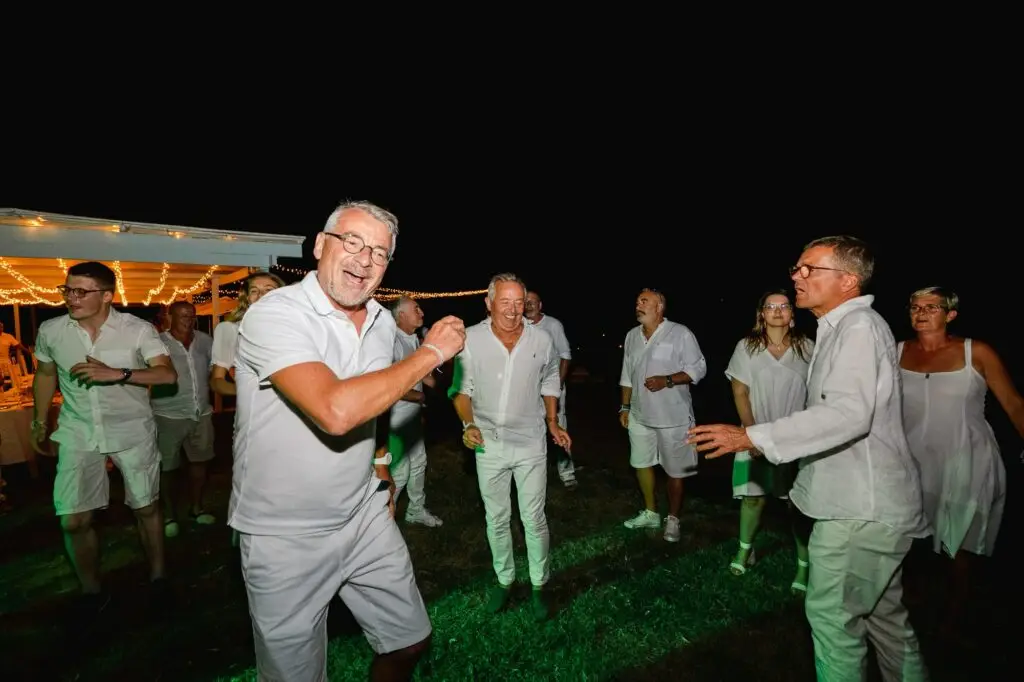 Invités dansant lors de la soirée de mariage en plein air en Crète, ambiance joyeuse et spontanée de nuit