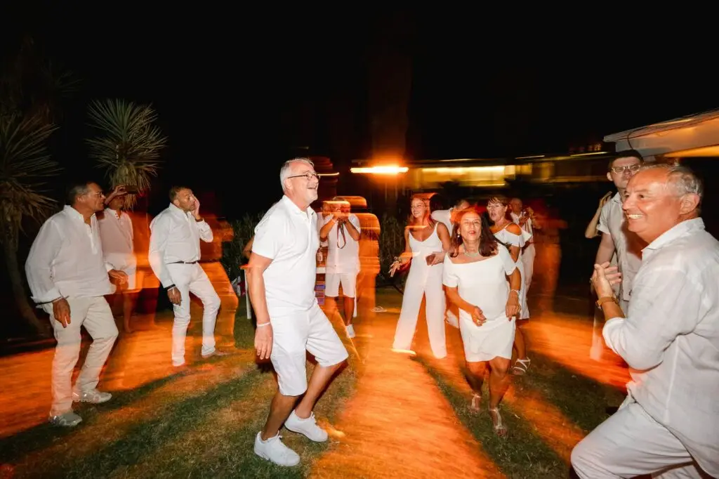 Groupe d’invités dansant lors d’un mariage en Crète, ambiance nocturne avec mouvements et traînées lumineuses