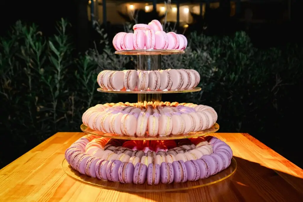 Présentation de macarons roses et pastel sur plusieurs étages lors d’un mariage en Crète, dessert raffiné en soirée