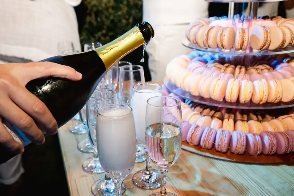 Coupe de champagne servie devant une pyramide de macarons lors d’un mariage en Crète, moment gourmand et festif