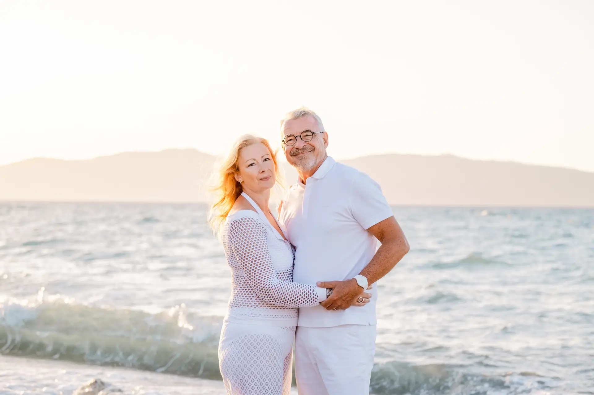 Couple de mariés posant ensemble au bord de la mer en Crète au coucher du soleil, lumière douce et atmosphère romantique