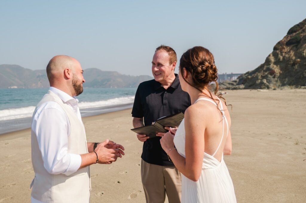 Mariés riant pendant leur cérémonie de mariage elopement sur la plage à San Francisco