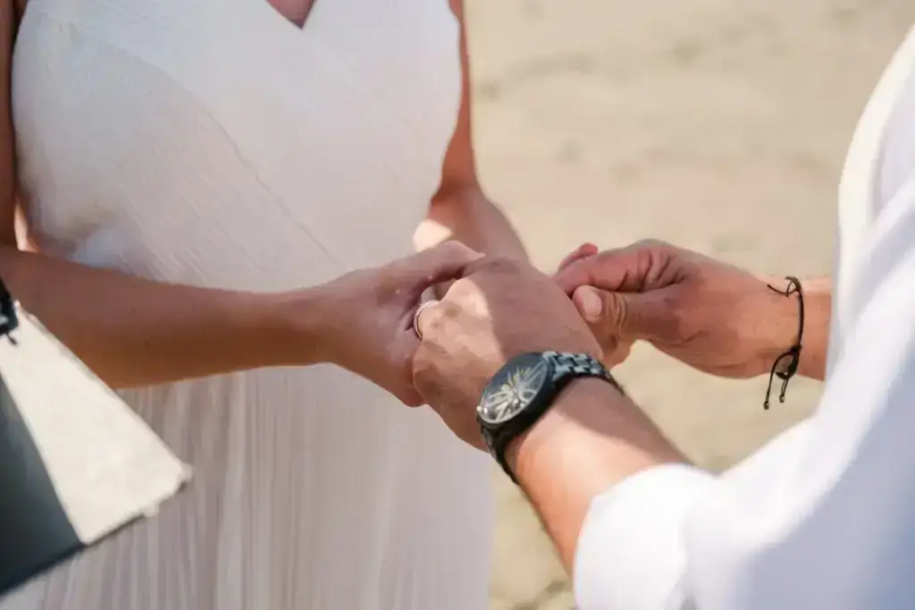 Mains des mariés enlacées après l’échange des alliances lors d’un elopement sur la plage à San Francisco